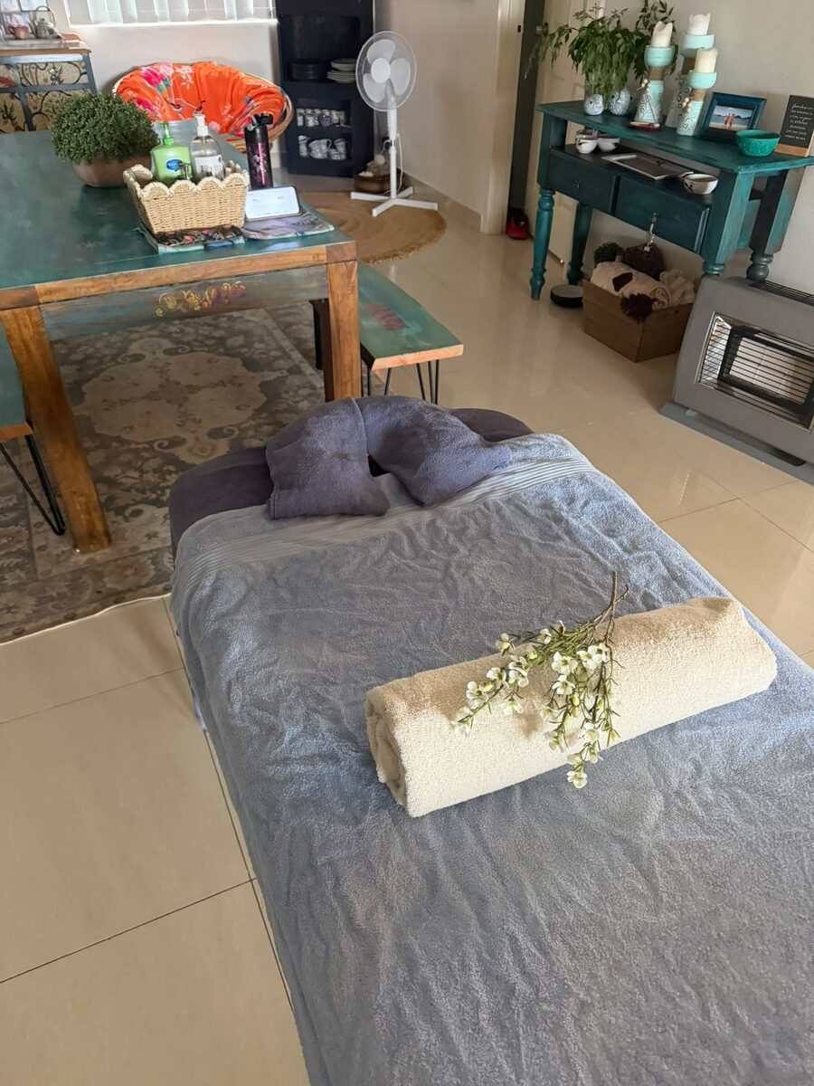 The treatment room by day, the massage table made up with fresh towels and a spray of flowers
